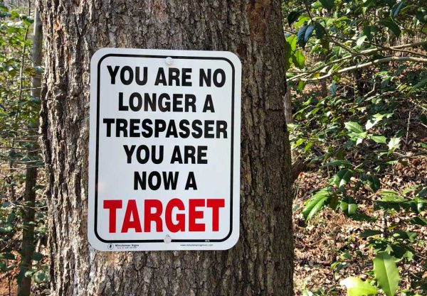 you are no longer a trespassing you are a target metal sign mounted on a tree
